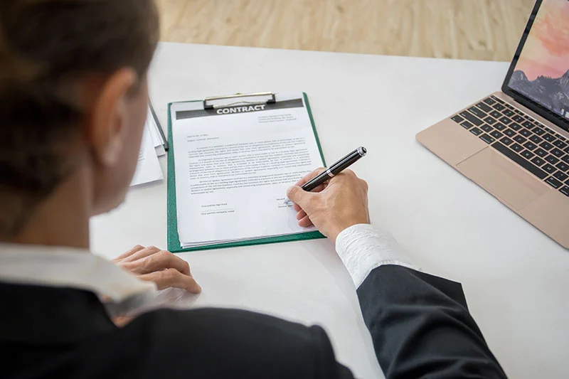 Une Femme est assise à un bureau et complète un formulaire.