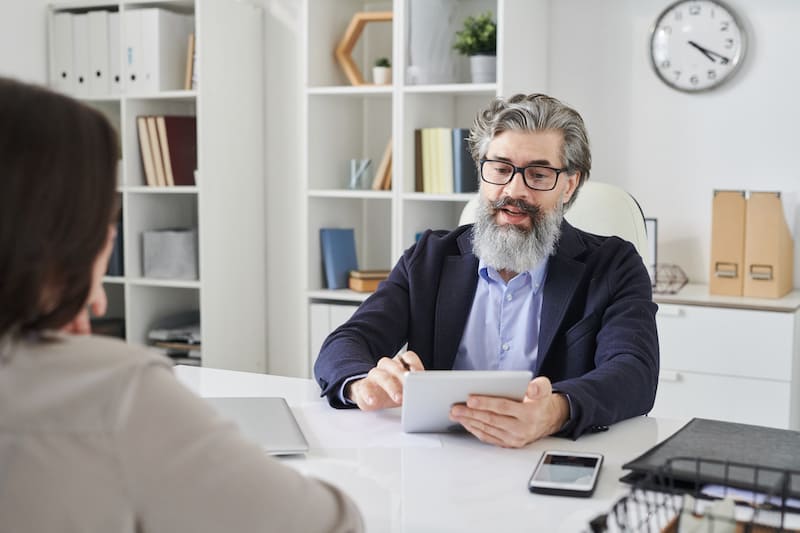 Un homme barbue avec des lunettes tient un document dans ses mains pour expliquer un contrat